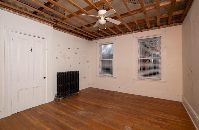 unfurnished room with ceiling fan, radiator heating unit, and dark hardwood / wood-style flooring