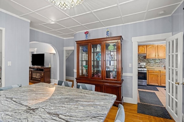 bedroom featuring arched walkways, light wood-style flooring, and crown molding
