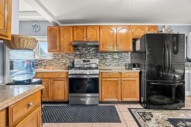 kitchen with stainless steel gas stove, freestanding refrigerator, decorative backsplash, and light countertops