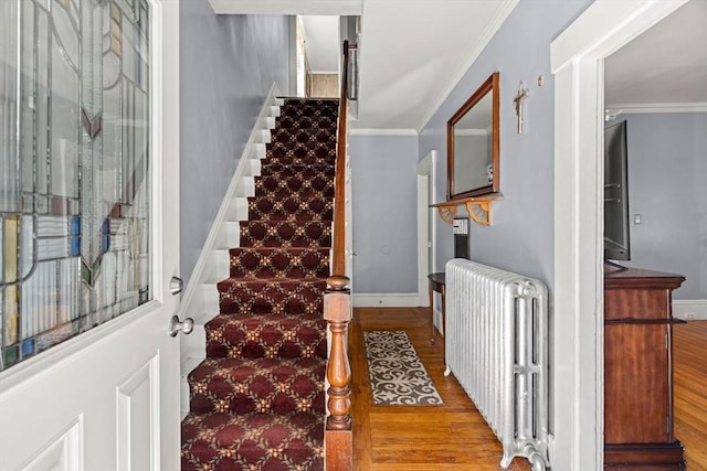 staircase featuring radiator, crown molding, and wood finished floors