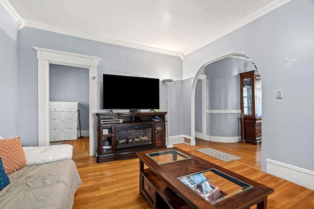 living room with arched walkways, ornamental molding, light wood finished floors, and baseboards