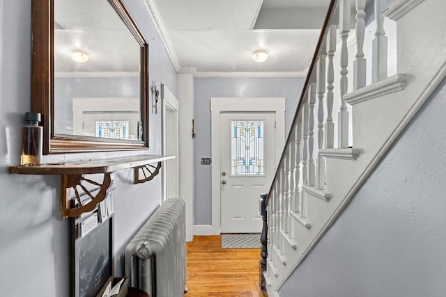 entrance foyer featuring radiator, wood finished floors, stairs, baseboards, and crown molding
