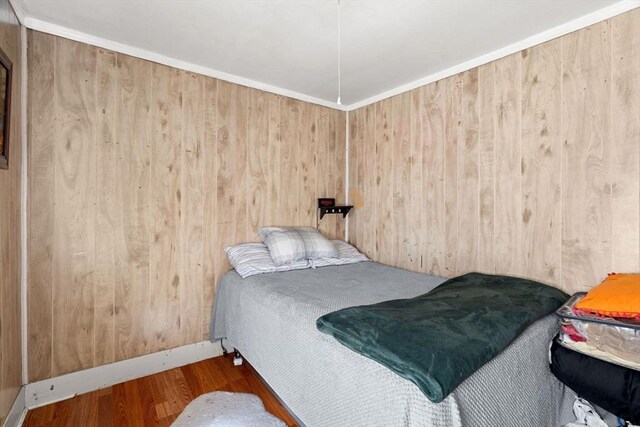 bedroom with wood walls and wood finished floors