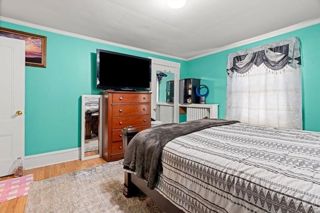 bedroom with wood finished floors, ornamental molding, and baseboards