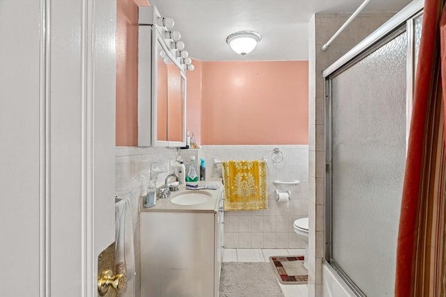 bathroom featuring tile walls, an enclosed shower, toilet, vanity, and tile patterned flooring