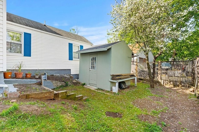 view of side of property with fence, an outdoor structure, and a storage shed