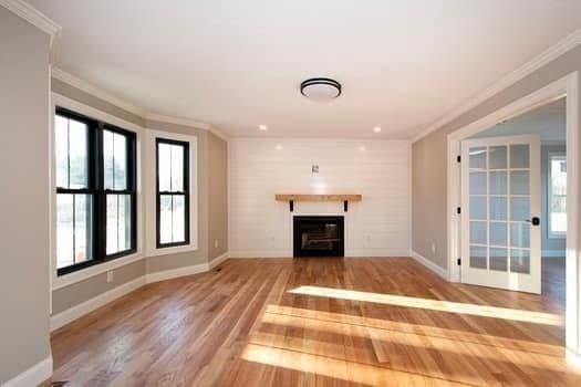 unfurnished living room with crown molding and a wealth of natural light