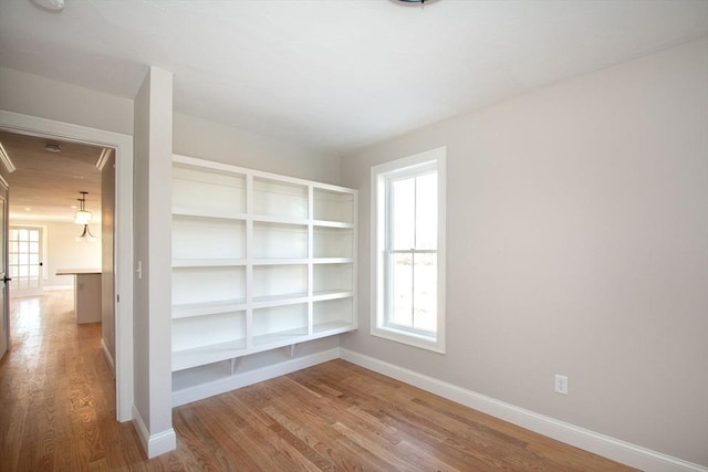 unfurnished room featuring hardwood / wood-style flooring and built in shelves