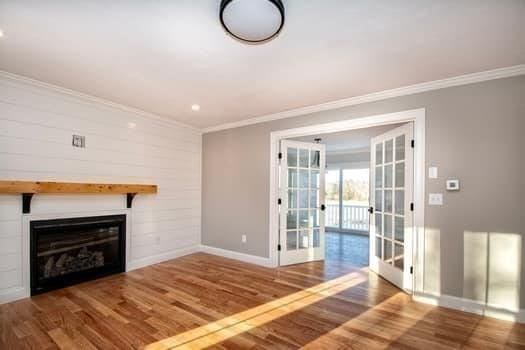 unfurnished living room with french doors, ornamental molding, and hardwood / wood-style floors