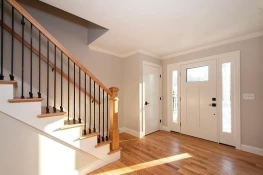 entryway with wood-type flooring and crown molding