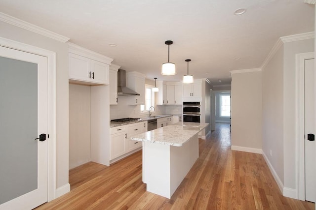 kitchen with white cabinets, a center island, wall chimney range hood, and appliances with stainless steel finishes