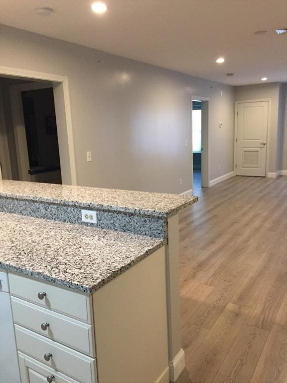 kitchen featuring light stone counters, recessed lighting, light wood-style flooring, and baseboards