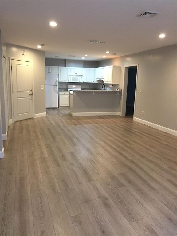 kitchen featuring white appliances, wood finished floors, visible vents, white cabinetry, and open floor plan