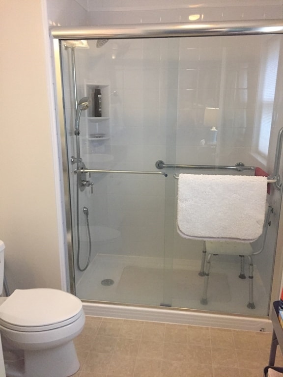 bathroom featuring a shower with shower door and toilet