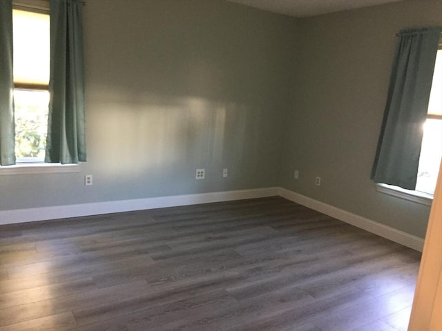 unfurnished room with dark wood finished floors and baseboards