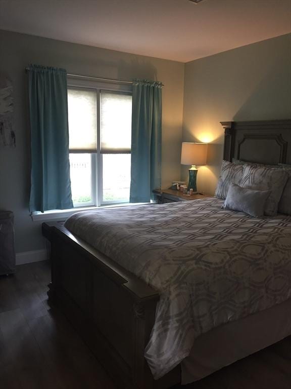 bedroom with dark wood finished floors and baseboards