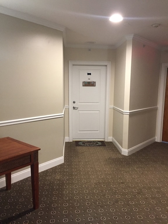 hallway featuring carpet floors, crown molding, and baseboards