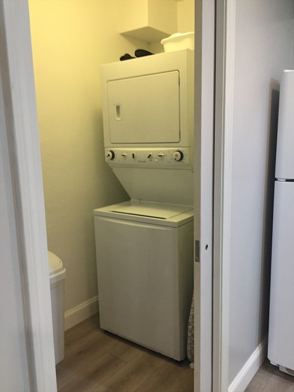 laundry room featuring stacked washer and dryer and light hardwood / wood-style floors