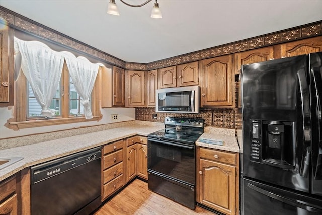 205 River St, Braintree, MA 02184 - kitchen with black appliances, light countertops, decorative backsplash, light wood-style floors, and brown cabinetry