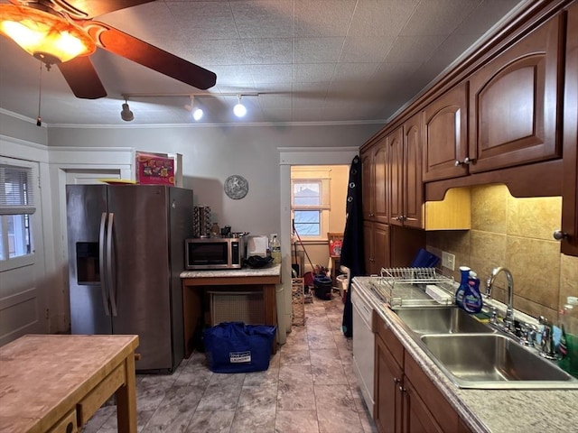 kitchen featuring rail lighting, appliances with stainless steel finishes, ceiling fan, ornamental molding, and sink