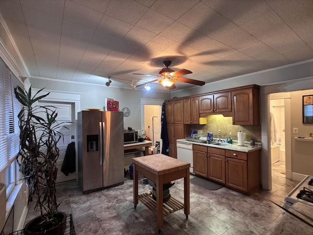 kitchen featuring appliances with stainless steel finishes, crown molding, ceiling fan, sink, and tasteful backsplash