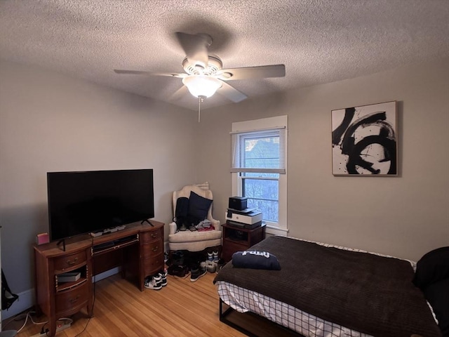 bedroom with light wood-type flooring, ceiling fan, and a textured ceiling