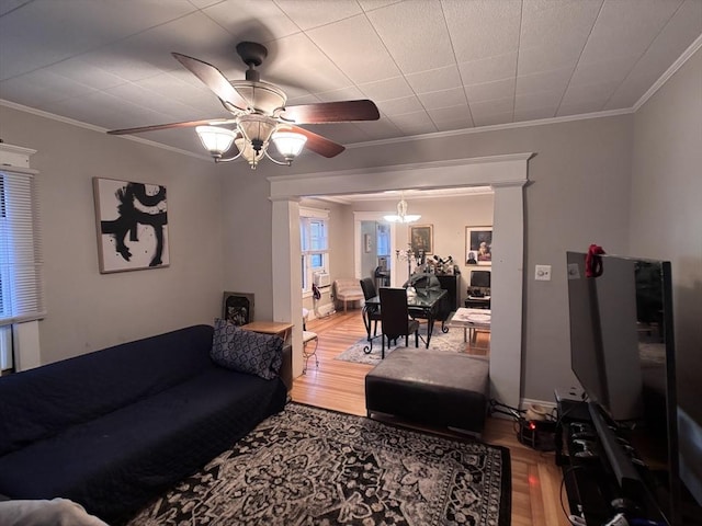 living room with wood-type flooring, ornamental molding, and ceiling fan