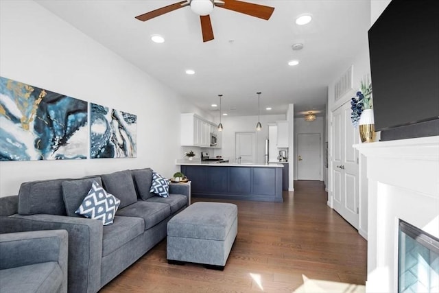 living room featuring dark wood-type flooring and ceiling fan