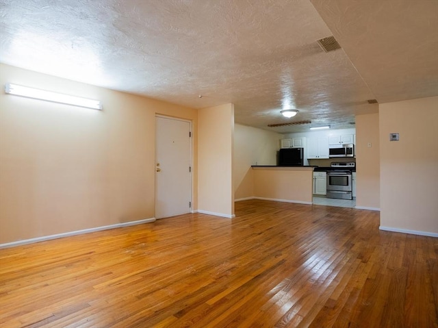 unfurnished living room with a textured ceiling and light wood-type flooring