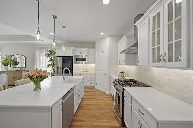 kitchen featuring white cabinetry, stainless steel appliances, a center island with sink, and pendant lighting