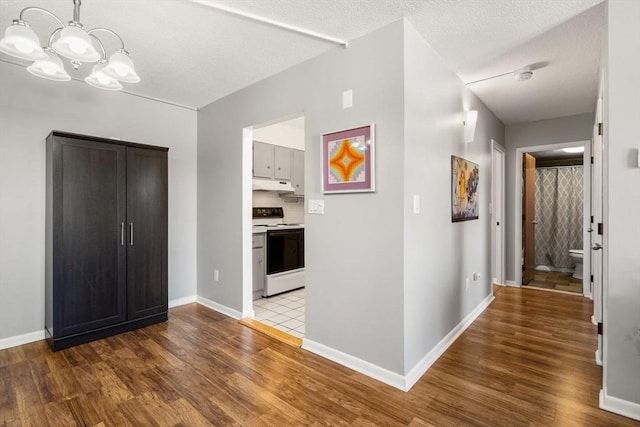 10 Williams St Unit 45, Watertown, MA 02472 - hallway featuring a textured ceiling, wood finished floors, an inviting chandelier, and baseboards