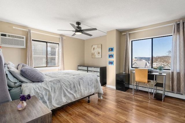 10 Williams St Unit 45, Watertown, MA 02472 - bedroom with baseboards, a ceiling fan, a textured ceiling, wood finished floors, and a wall unit AC