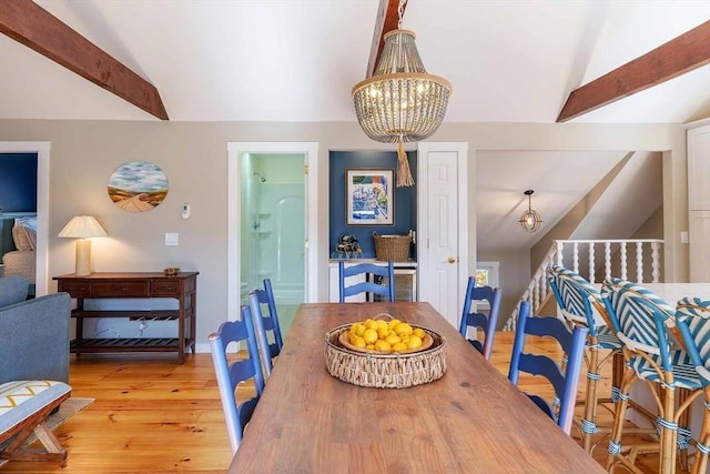 dining area featuring vaulted ceiling with beams, a chandelier, and light wood-type flooring