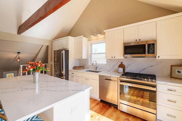 kitchen with sink, a center island, lofted ceiling with beams, appliances with stainless steel finishes, and white cabinets