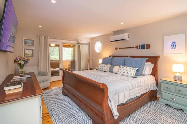 bedroom featuring light wood-type flooring, a wall unit AC, and access to outside