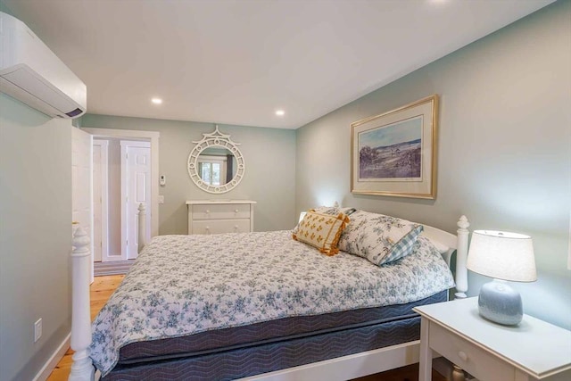 bedroom featuring hardwood / wood-style flooring and a wall unit AC