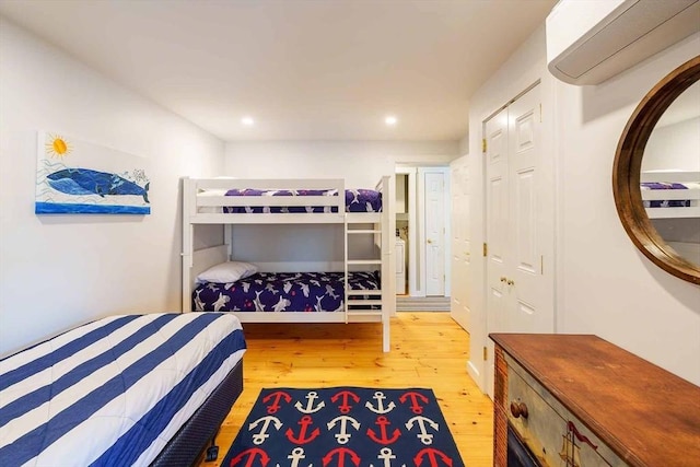 bedroom featuring a wall mounted air conditioner and light hardwood / wood-style floors