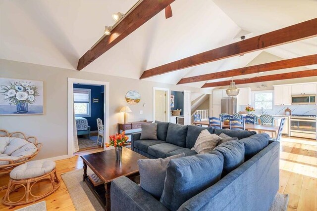 living room featuring beam ceiling, high vaulted ceiling, and light wood-type flooring