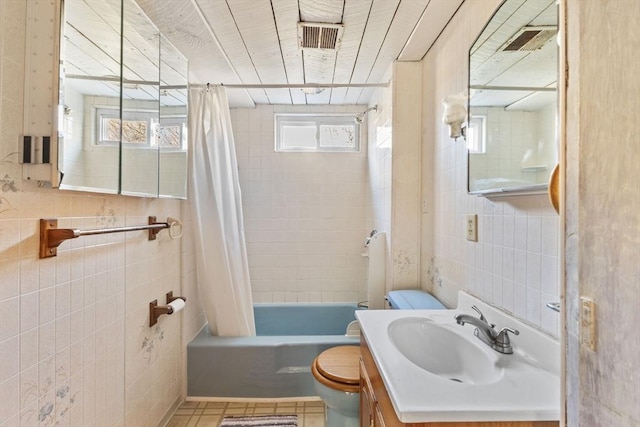 full bathroom with vanity, shower / bath combination with curtain, tile patterned flooring, toilet, and tile walls