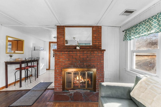 living room with hardwood / wood-style floors, a brick fireplace, and plenty of natural light