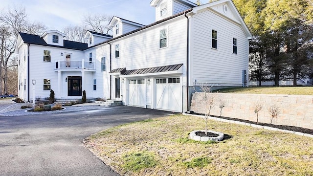 view of side of property with a lawn, a garage, and a balcony