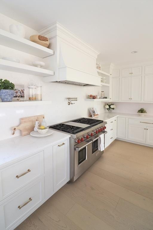 kitchen featuring double oven range, white cabinetry, and light wood-type flooring