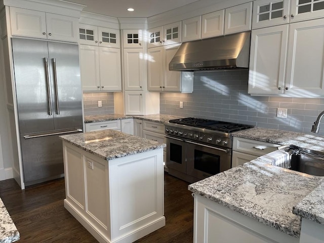 kitchen with white cabinets, a center island, light stone countertops, and high quality appliances