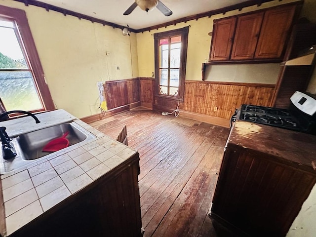 205 Saint James Ave, Springfield, MA 01109 - kitchen with tile counters, dark wood-style floors, range with gas stovetop, a wainscoted wall, and a ceiling fan