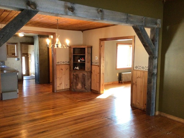 unfurnished living room featuring dark wood-type flooring, wood ceiling, radiator, and a notable chandelier