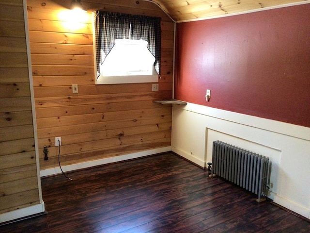 spare room with dark hardwood / wood-style floors, radiator heating unit, wooden walls, and vaulted ceiling