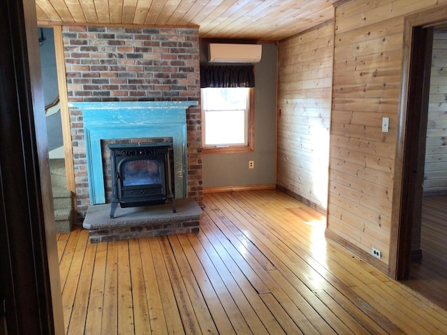 unfurnished living room featuring wood ceiling, a wall mounted air conditioner, a wood stove, wooden walls, and hardwood / wood-style flooring