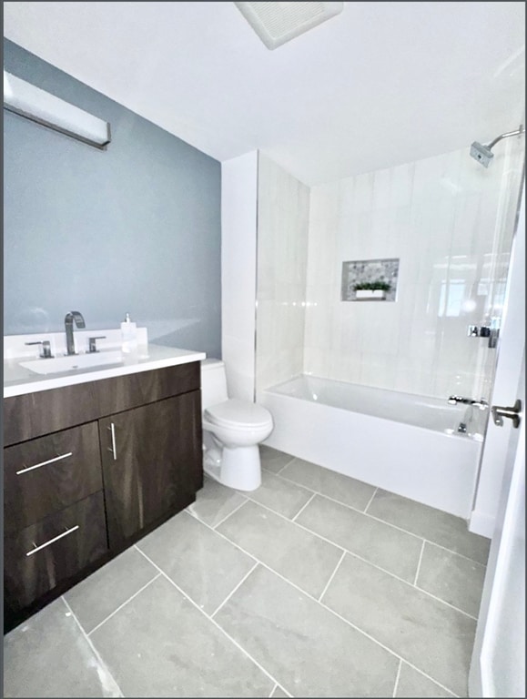 full bathroom with tile patterned floors, tiled shower / bath, vanity, and toilet