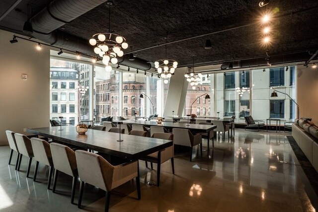 dining area with a wealth of natural light, floor to ceiling windows, and a notable chandelier