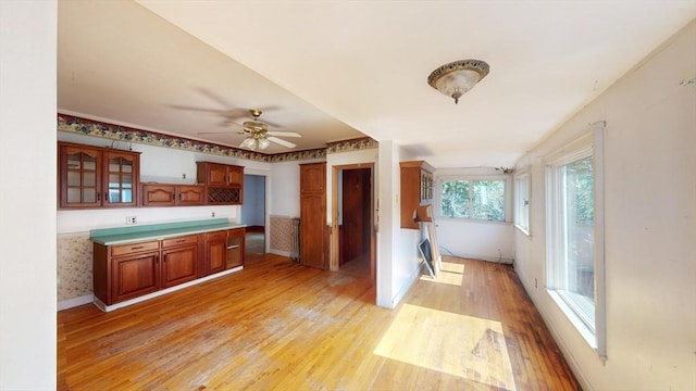 15-17 Brockton Ave, Haverhill, MA 01830 - kitchen featuring light wood-style floors, a ceiling fan, glass insert cabinets, brown cabinets, and baseboards